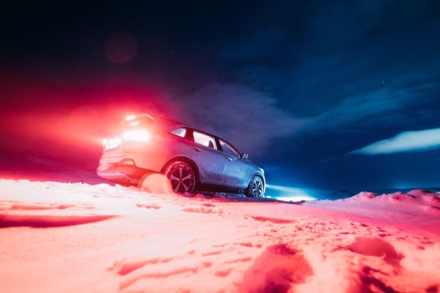A car drives through snow in the dark, which Veritas Global Protection can help with